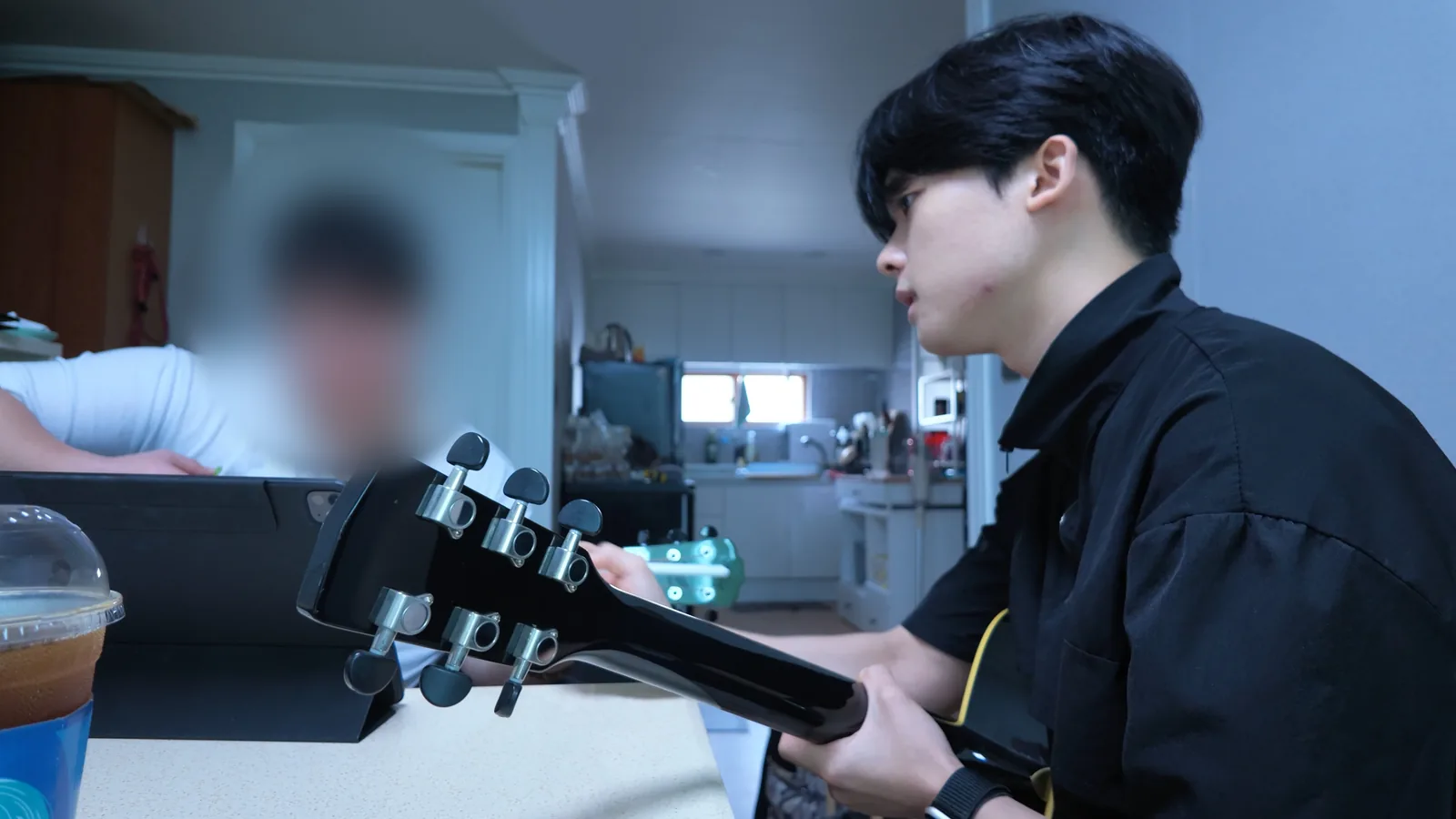 약속한 실내 공간에서 태블릿 자료를 보며 진행하는 방문 기타 레슨